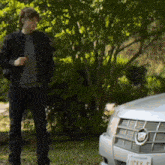 a man stands in front of a car with a license plate that says lucky 5