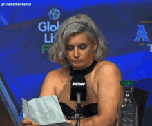 a woman is sitting in front of a microphone that says aew on it