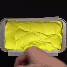 a person is spreading yellow frosting in a loaf pan ..