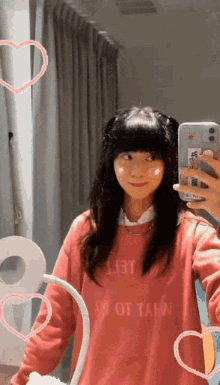 a girl taking a selfie in front of a mirror wearing a pink sweater that says jet on it