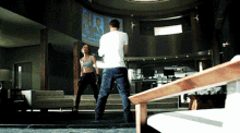 a man in a white shirt stands in front of a woman in a crop top in a living room