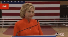 a woman stands at a podium with a microphone in front of an american flag and abc news.com written on the bottom
