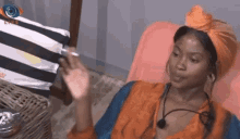 a woman is sitting in a chair wearing a turban and smoking a cigarette .