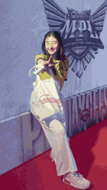 a woman stands on a red carpet in front of a wall that says mlbb professional league