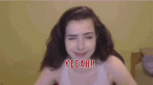 a woman with her arms outstretched is wearing a white tank top with yeeah written on it