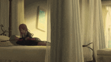 a girl is laying on a man 's stomach in a bedroom