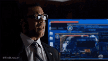a man in a suit and tie is looking up at something in the dark .