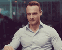 a man wearing a light blue shirt is smiling