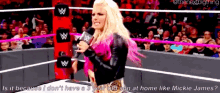 a woman is standing in a wrestling ring holding a microphone and talking into it .