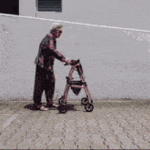 an elderly woman is pushing a pink walker down a brick sidewalk