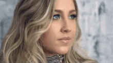 a woman with long blonde hair and blue eyes is wearing a choker .