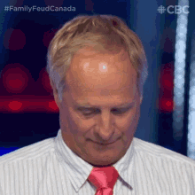 a man with a bald head is wearing a pink tie and a striped shirt ..