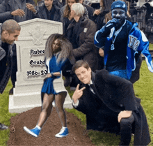 a group of people are gathered around a grave of aubre graham