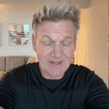 a man wearing a black shirt is making a funny face with his eyes closed