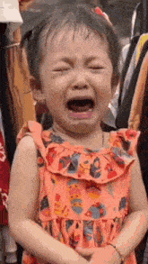 a little girl is crying with her eyes closed and her mouth open .