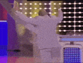a man in a white suit is dancing in front of a colorful backdrop
