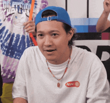 a man wearing a white shirt and a blue hat has the word nin on his shirt
