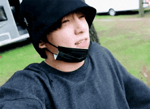 a young man wearing a black bucket hat and a black mask on his face .