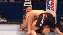 two men are wrestling in a ring with one wearing shorts that say smmash on them