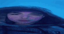 a woman with a purple mask on her face looks at the camera