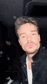 a man with a beard and mustache is wearing a black jacket and a white shirt .