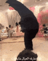 a man is doing a handstand in a room with balloons .
