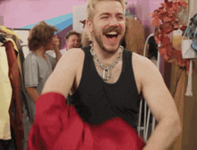 a man wearing a black tank top is laughing