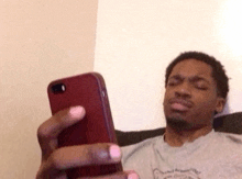 a man is sitting on a couch holding a cell phone in his hand .