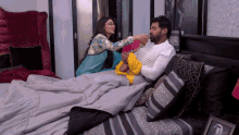 a man and a woman are laying on a bed and the woman is holding the man 's hand