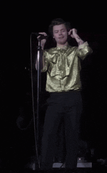 a man in a yellow shirt is singing into a microphone on stage
