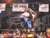 a wrestling match is going on in front of a banner that says joe hansen
