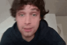 a man in a black hoodie is making a funny face while looking at the camera .