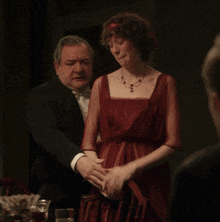 a man in a tuxedo and a woman in a red dress are sitting at a table