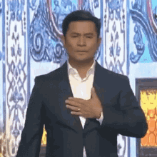 a man in a suit holds his hand to his heart