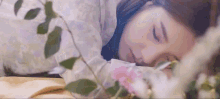 a woman is laying on a bed next to flowers and leaves .