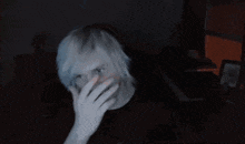 a man with white hair covering his face with his hand