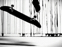 a black and white photo of a person riding a black skateboard
