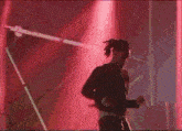 a man is standing on a stage in front of a red light and holding a microphone .