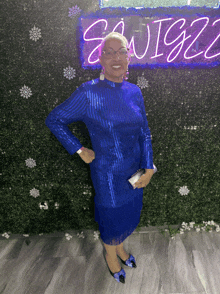 a woman in a blue dress stands in front of a sign that says swigz
