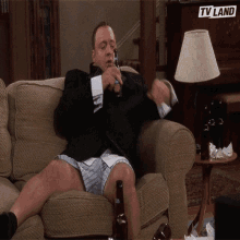 a man sitting on a couch with a bottle of beer and a tv land logo