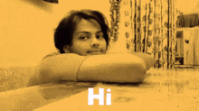 a woman sits at a table with her head resting on her elbow and the word hi written on the table in front of her