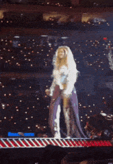 a woman in a white dress is dancing on a stage in front of a crowd