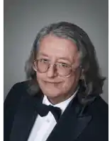 a man wearing glasses and a tuxedo is smiling