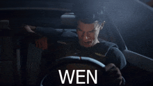 a man is driving a car with the word wen on the bottom