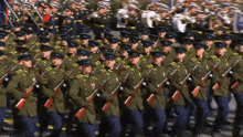 a large group of soldiers marching in a line with a band in the background
