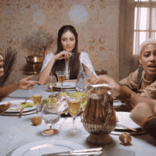 a group of people are sitting at a table with plates of food and wine glasses