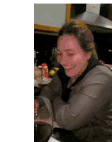 a woman covering her face with her hand while sitting in a kitchen