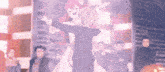a couple of anime characters are dancing together in front of a crowd of people .