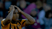 a soccer player wearing a shirt that says umbro holds his head in his hands