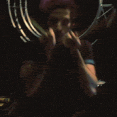 a man in a blue shirt is holding a pair of drums in front of his face